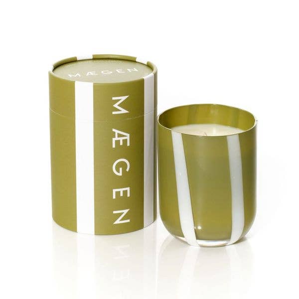 Green candle in a cylindrical container with 'Mågen' branding on a white background