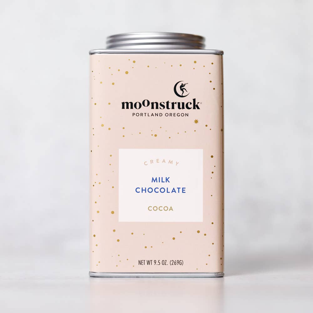 A tin of Moonstruck Portland Oregon milk chocolate cocoa, with a speckled background and a label that reads 'Milk Chocolate Cocoa'.