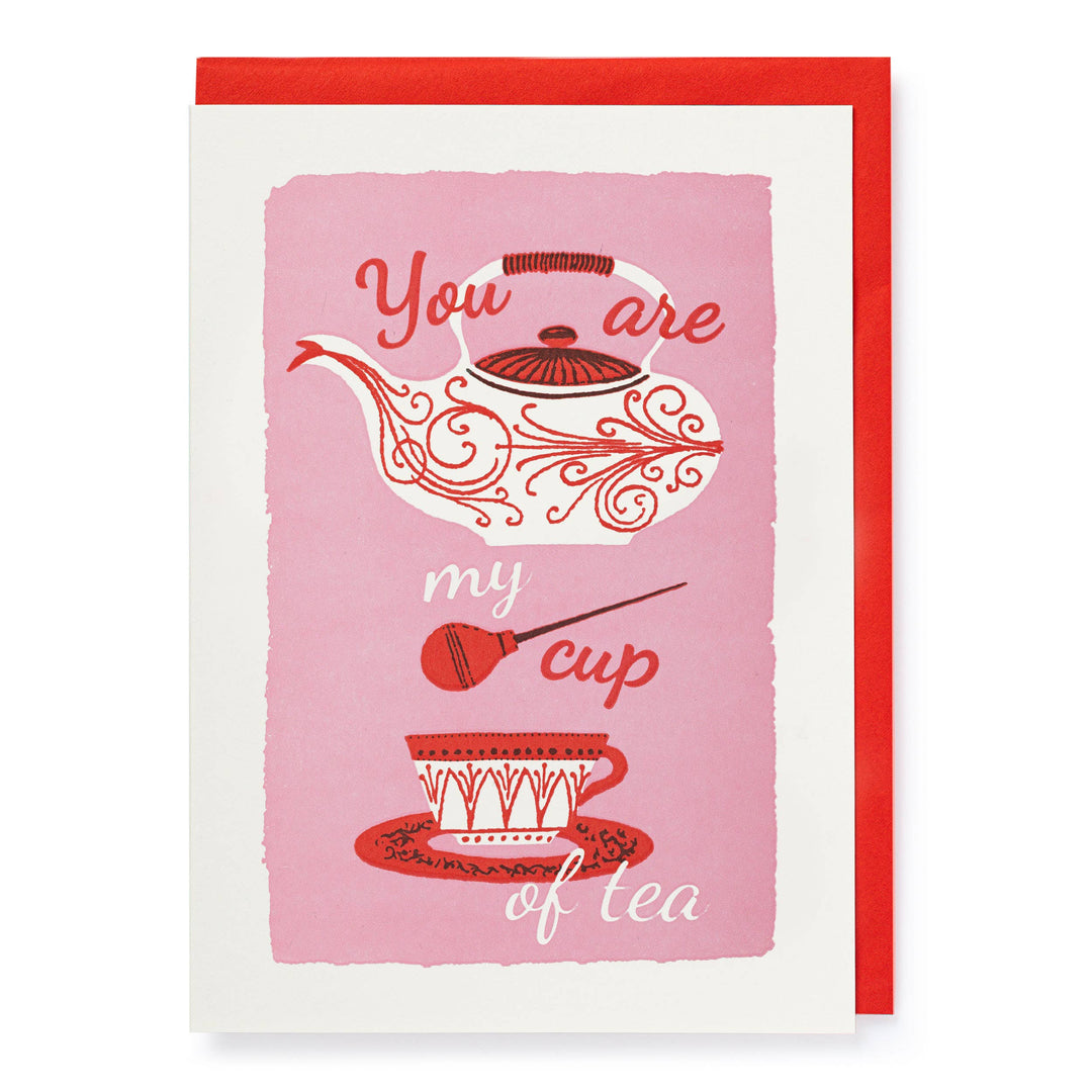 A greeting card with a pink background featuring a white teapot and teacup with red and white floral patterns. The text on the card reads 'You are my cup of tea'.