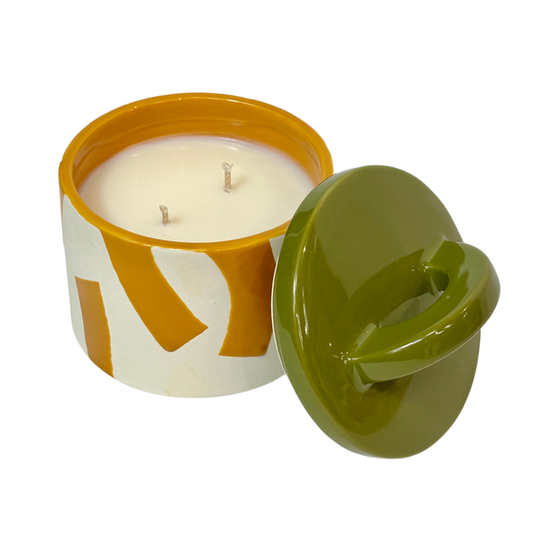 Candle in a decorative container with a green lid on a white background
