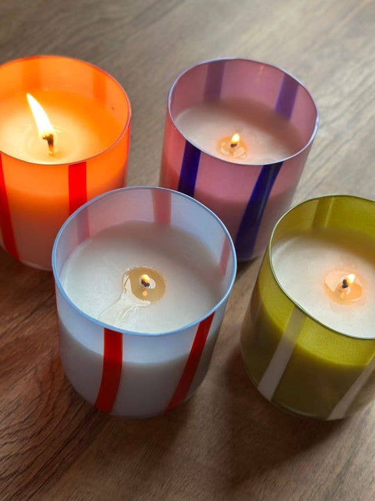 Four colorful striped candles on a wooden surface