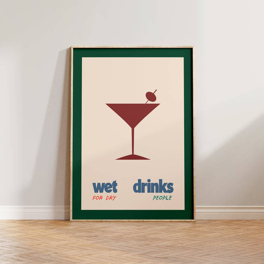A framed poster with a graphic of a martini glass and the text 'wet drinks for dry people' on a wall.