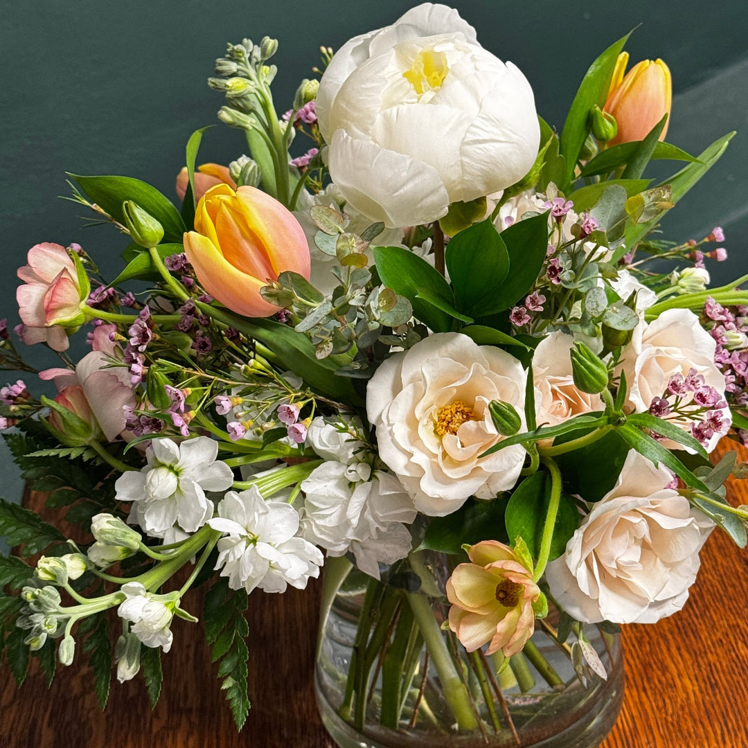 Floral arrangement in a glass vase on a wooden surface.