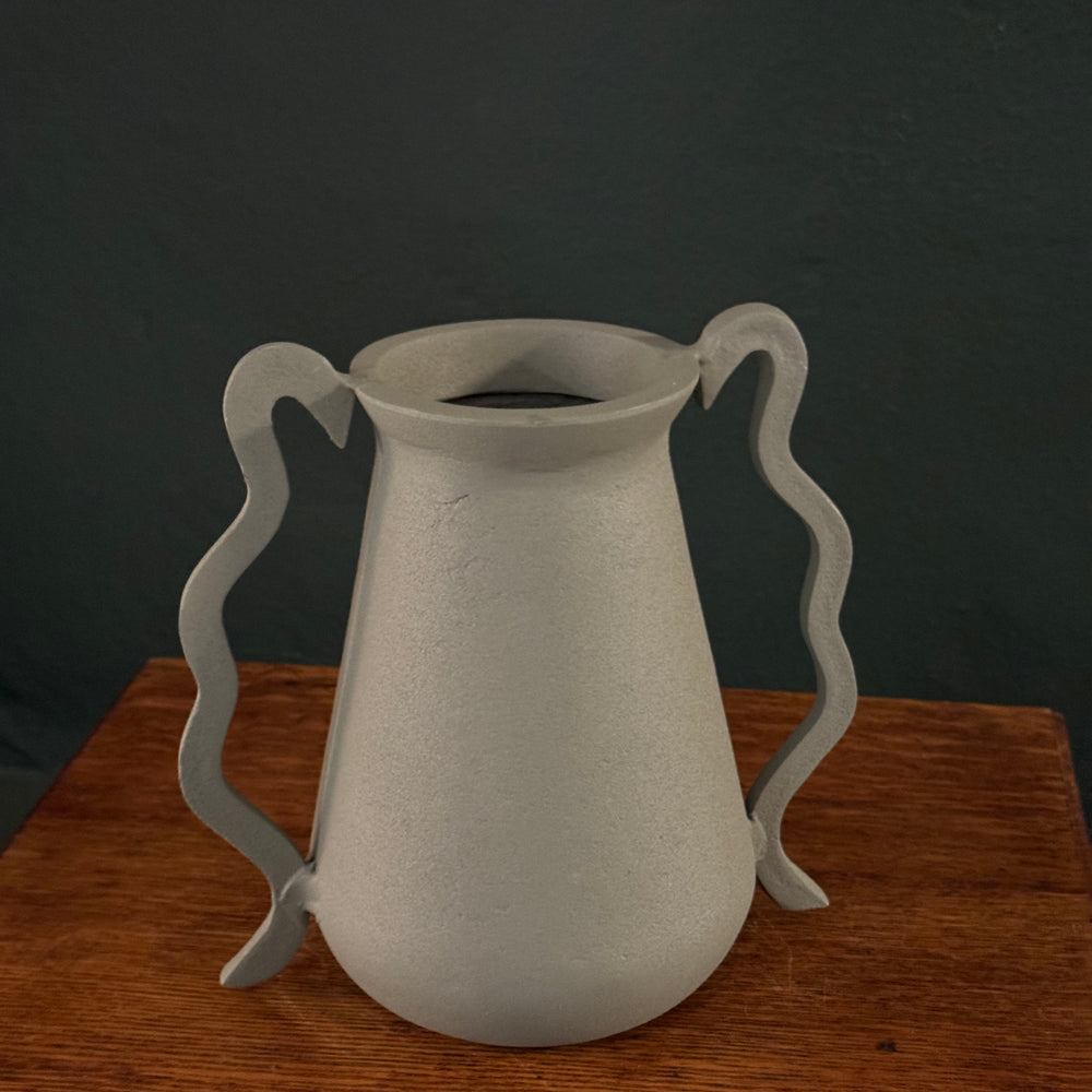 White ceramic vase with wavy design on a wooden surface