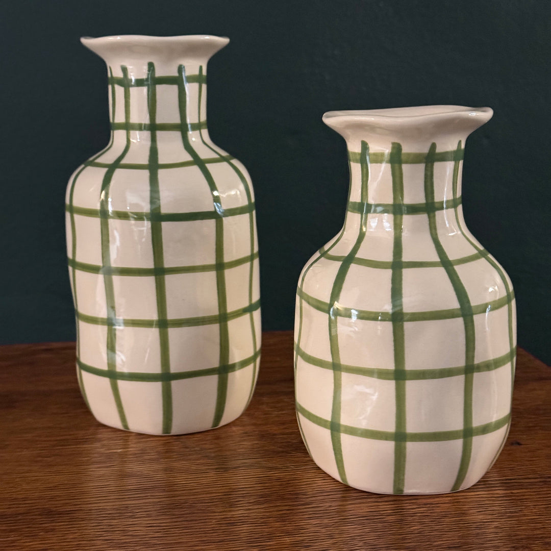 This image displays two ceramic vases with a charming picnic theme. The vases are painted with a unique hand-painted grid pattern in green on a glossy white background, emphasizing their artisanal origin.
