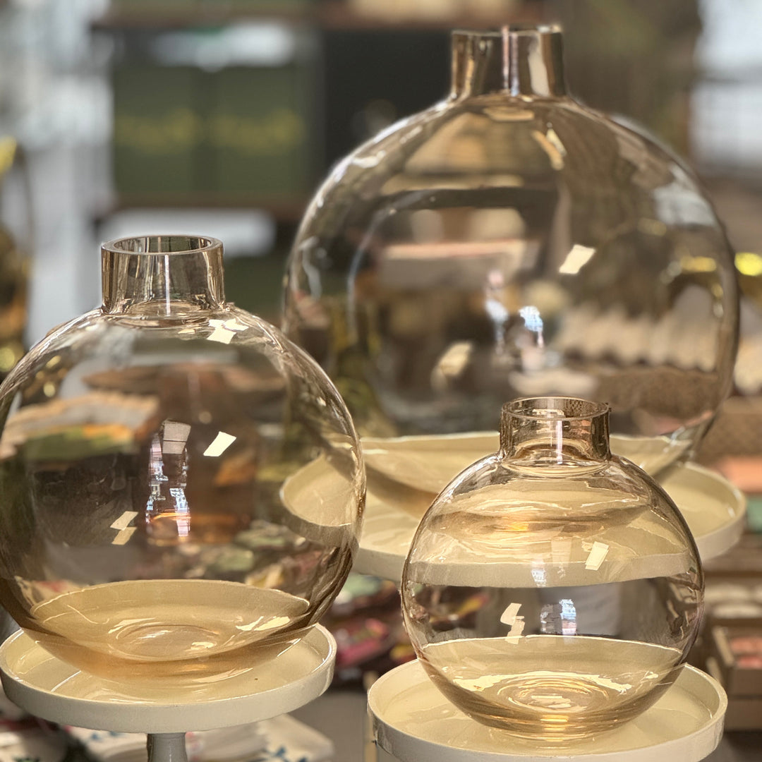 Three transparent glass vases of different sizes on white stands.