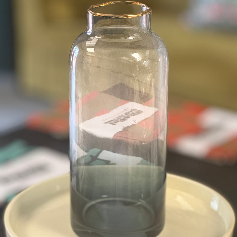 Clear glass bottle with gold rim on a white plate, blurred background