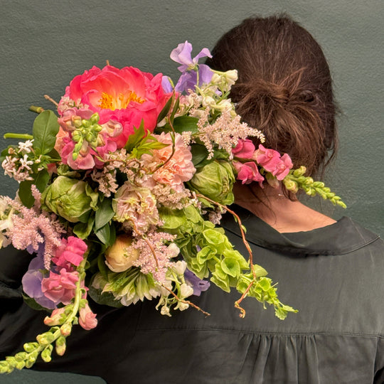 Person holding a colorful bouquet of flowers against a plain background