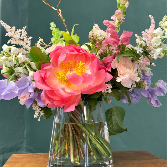 Floral arrangement in a clear vase against a green background