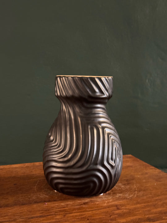 Decorative metal knob on a wooden surface with a dark green background
