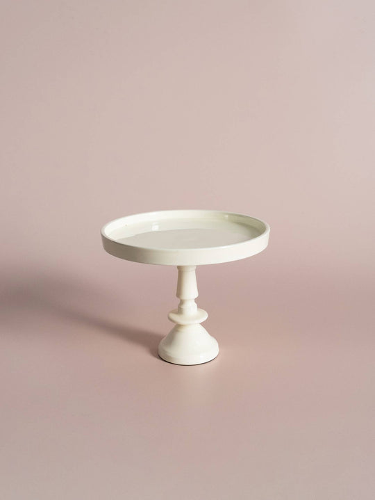 A small off white pedestal with a vintage-inspired design, featuring a single circular platform on top and a sturdy base.