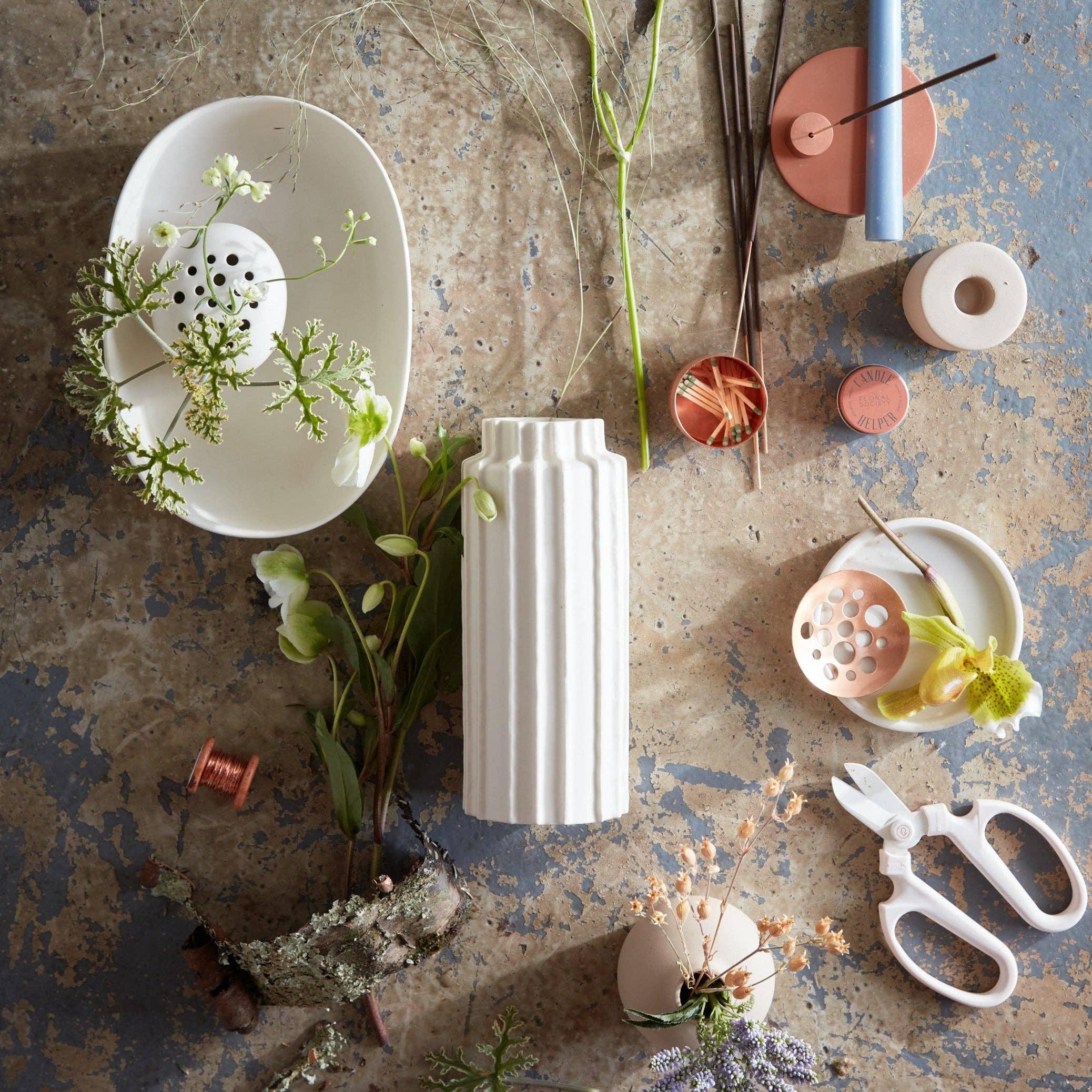 Floral arrangement tools and white vase with fresh blooms on rustic surface