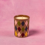 Candle in a diamond patterned container on a pink background