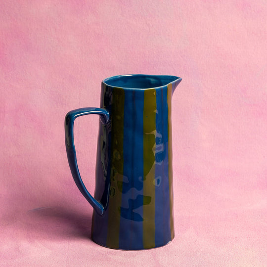 Blue ceramic pitcher on a pink background