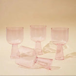 Set of pink glass goblets on a beige background