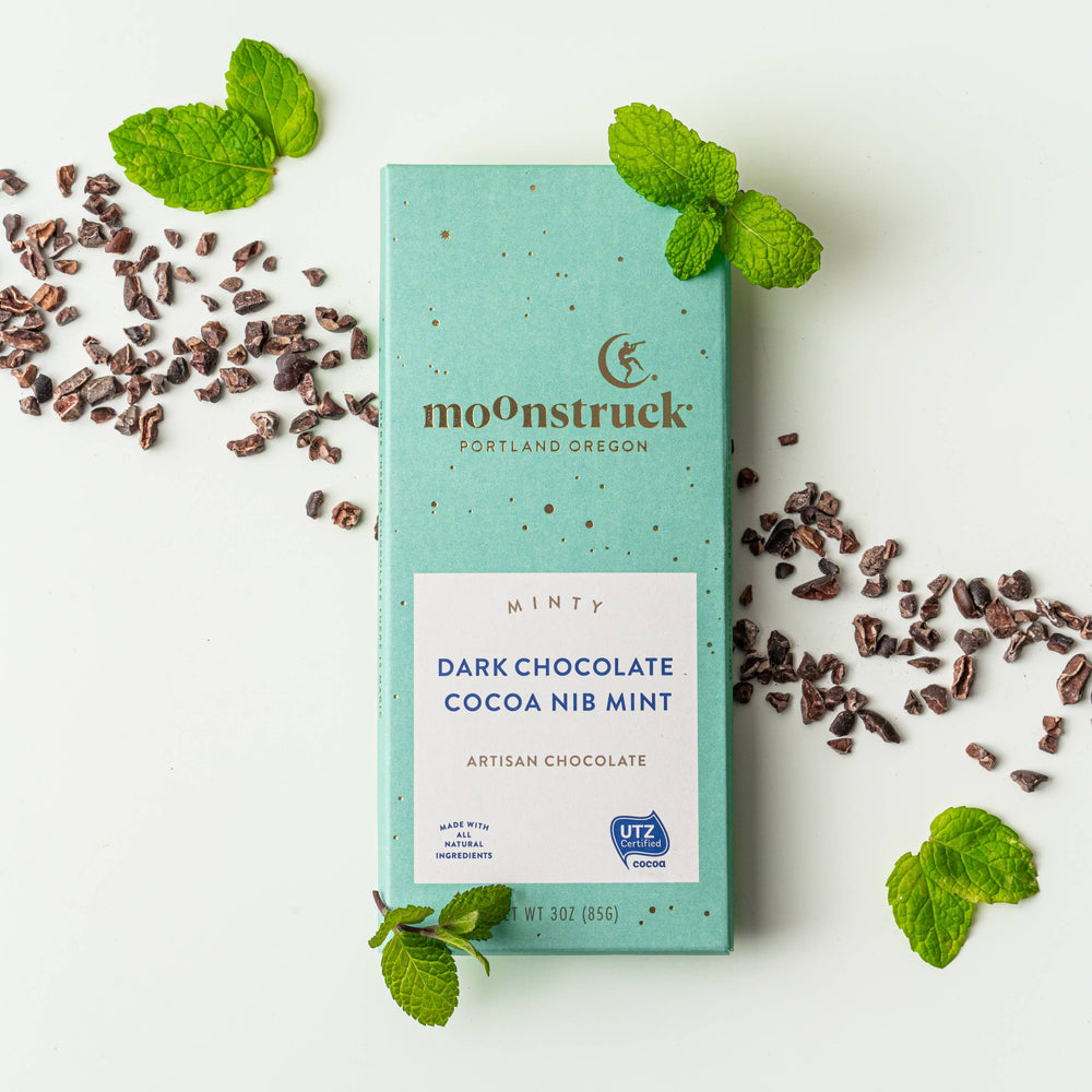 Mint chocolate bar with cocoa nibs and mint leaves on a white background
