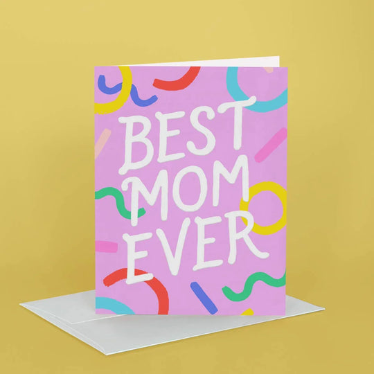 Greeting card with 'Best Mom Ever' text on a pink background with colorful shapes, on a yellow background.