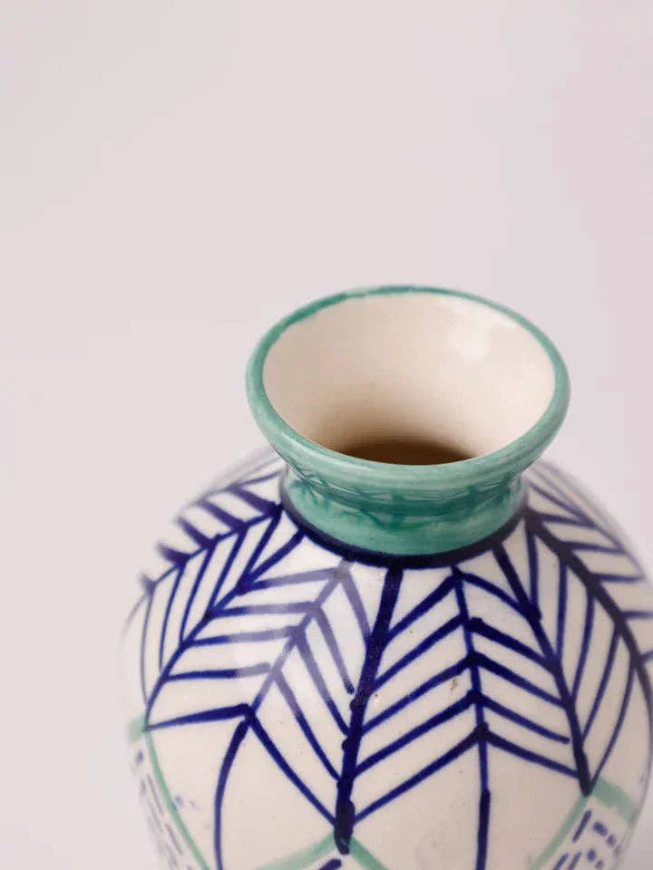 Hand-painted ceramic vase with blue leaf patterns and green rim, ideal for floral arrangements