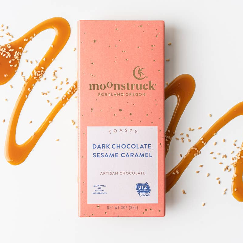 Moonstruck dark chocolate sesame caramel bar packaging on a white background with caramel drizzle.