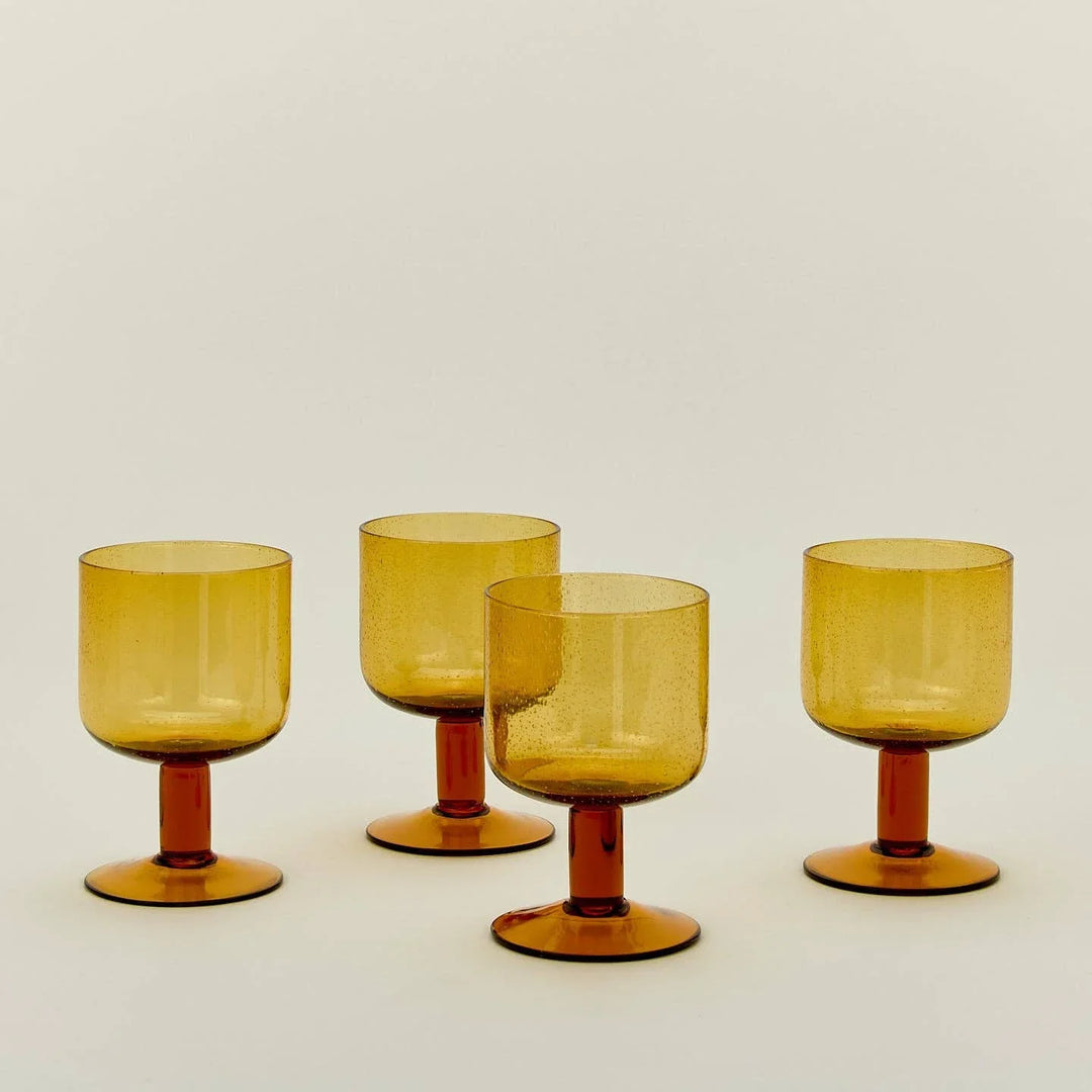 Amber glass goblets with speckled texture and red stems, ideal for elegant table settings.