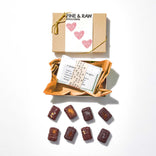 Box of Fine & Raw chocolate with a card and chocolate pieces on a white background