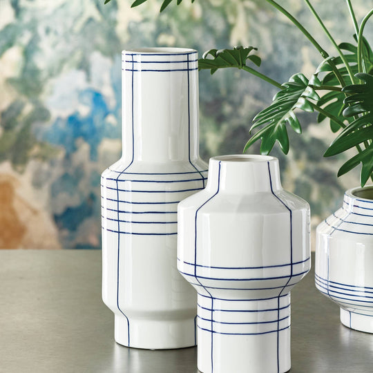 White vases with blue lines on a table with a blurred background