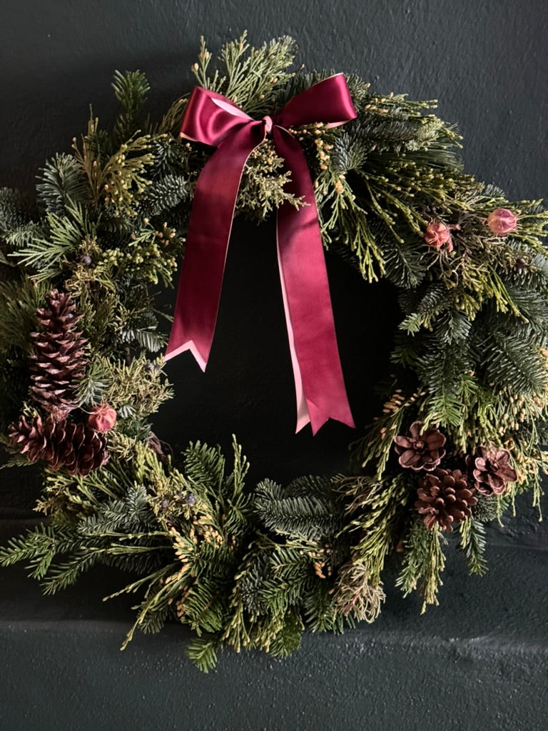 mixed evergreen wreath with pinecones and a red and pink bow
