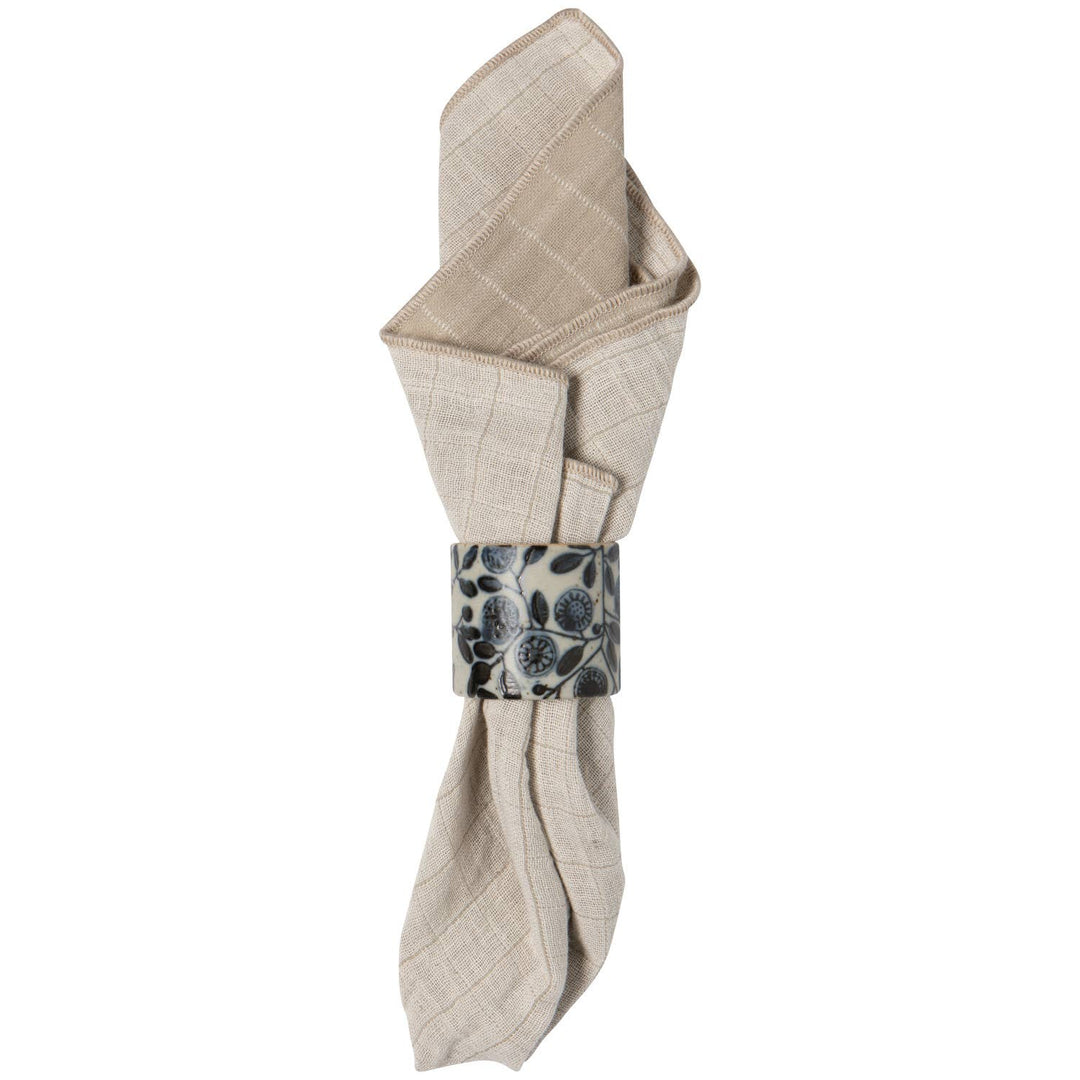 Folded beige napkin with a decorative napkin ring on a white background