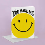Card with yellow smiley face and text 'You Make Me' on a purple background