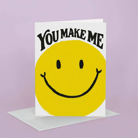 Card with yellow smiley face and text 'You Make Me' on a purple background