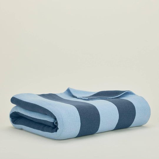 Folded blue and gray striped blanket on a beige background