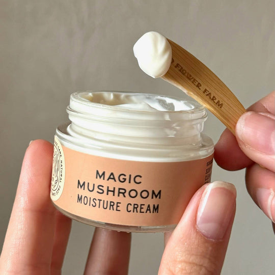 Magic Mushroom Moisture Cream jar with a wooden applicator on a neutral background