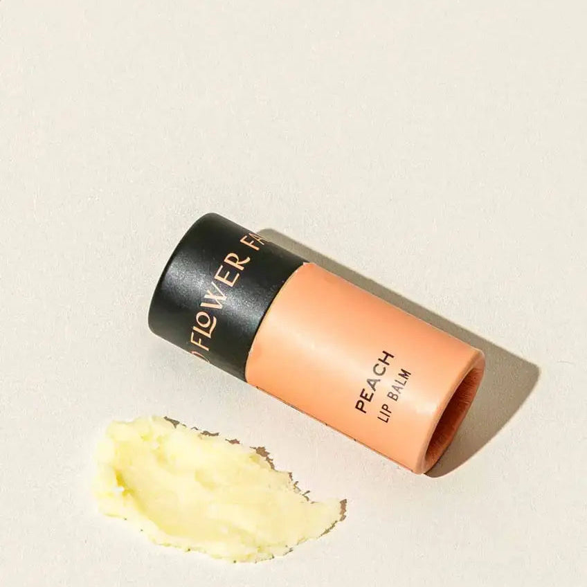 Flower Beauty peach lip balm on a beige background