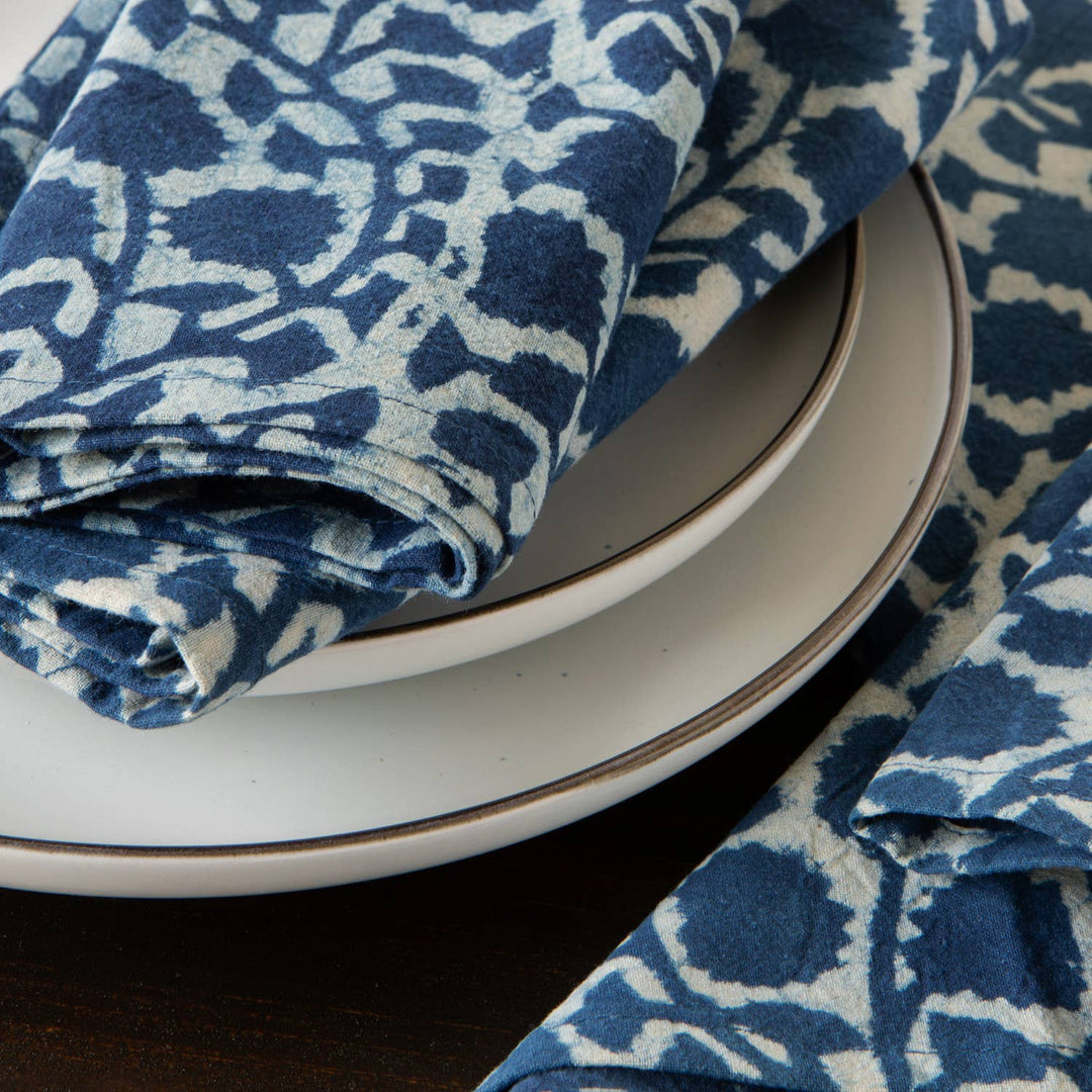 Stack of white plates with a blue and white patterned cloth on a dark surface