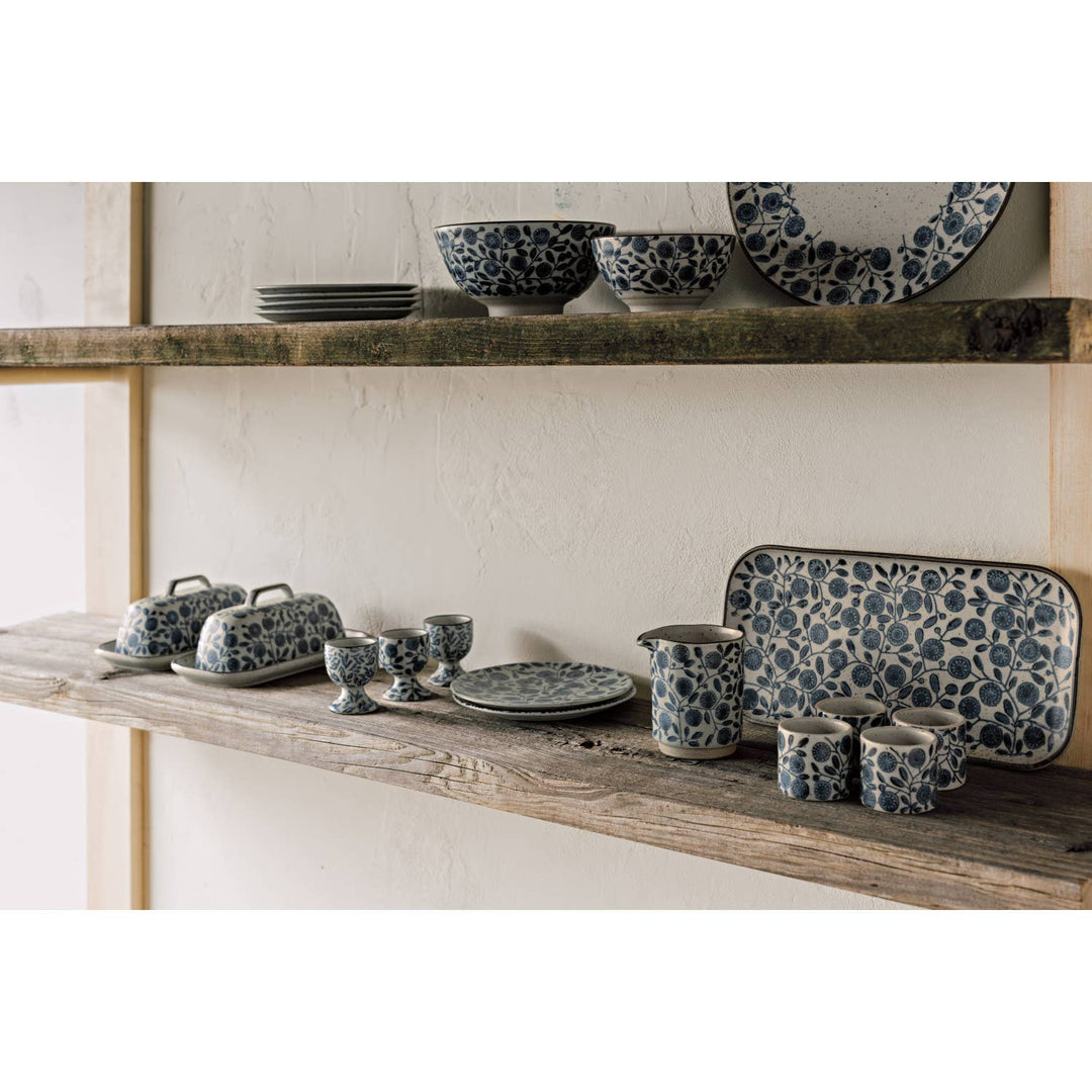 Set of ceramic dishes with blue floral patterns on wooden shelves.