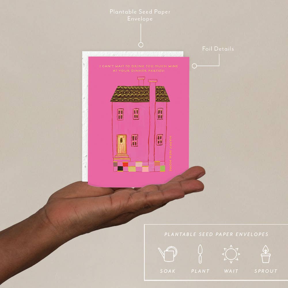 Hand holding a pink seed paper envelope with house illustration against a beige background