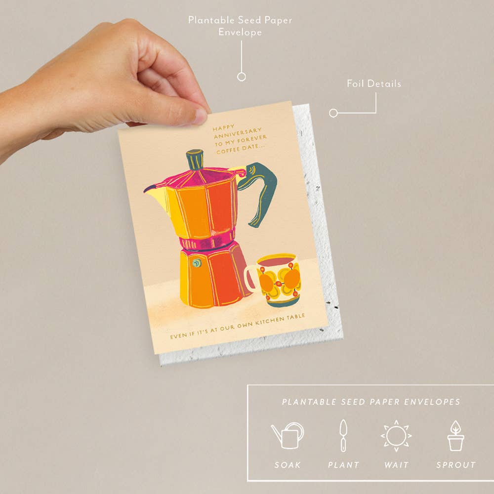 Hand holding a plantable seed paper envelope with a colorful illustration of a coffee maker on a beige background.