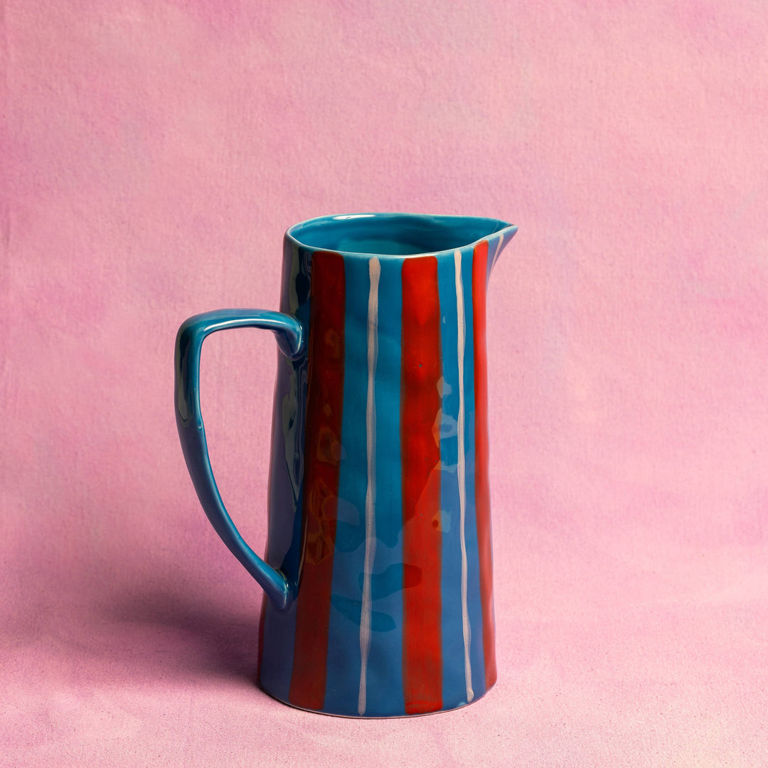 Striped ceramic pitcher on a pink background