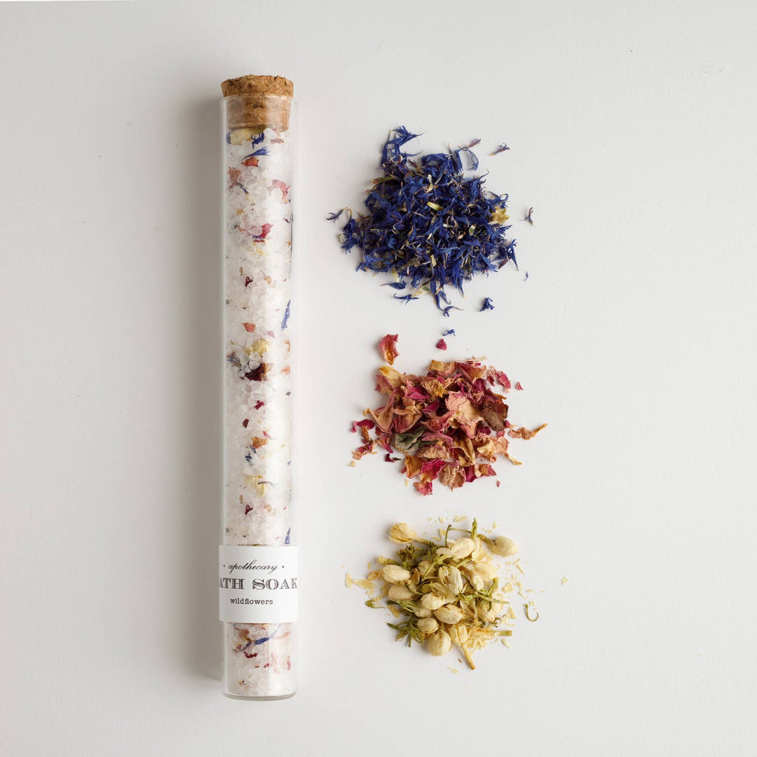 Tube of bath salts with dried flowers on a light gray background
