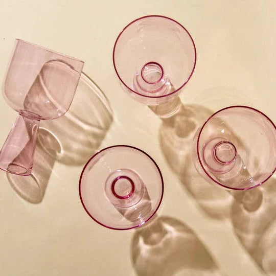 Set of pink glass goblets on a beige background