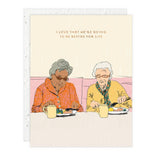Card with illustration of two elderly women sitting at a table, enjoying a meal together.
