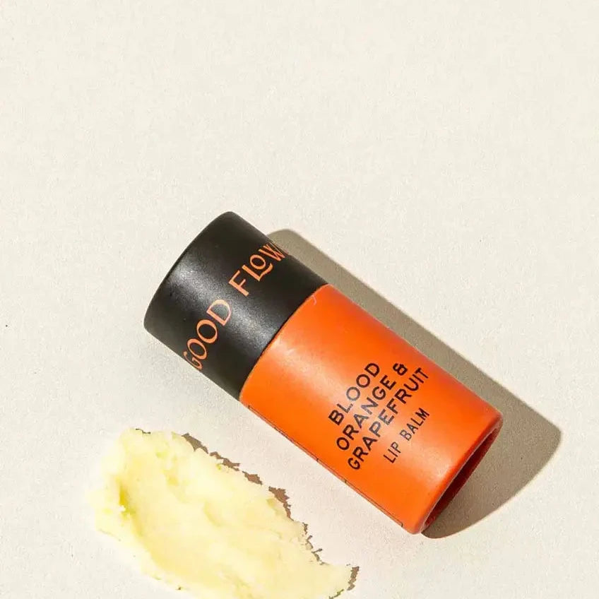 Lip balm stick with 'Good Flow' branding on a beige background