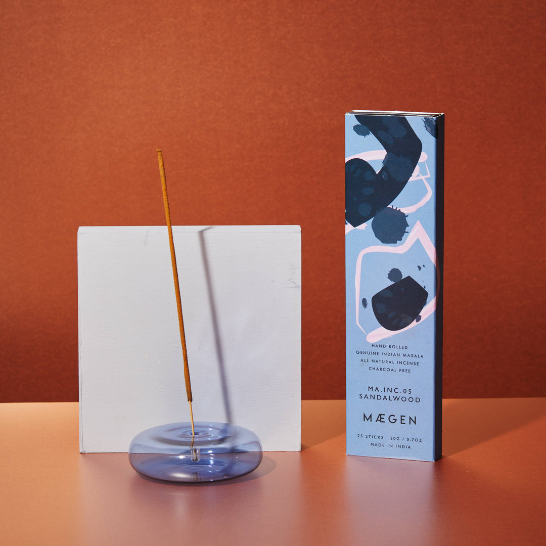 Incense stick and its packaging on a wooden surface with an orange background