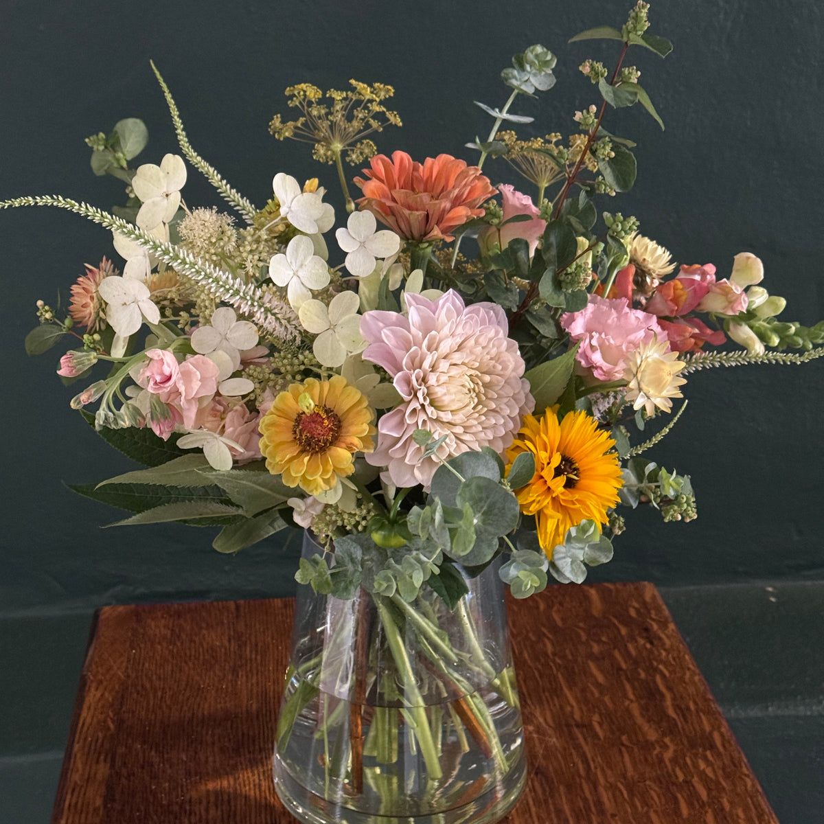 Floral arrangement with a clear glass vase against a dark background