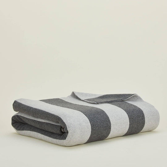Folded gray and white striped blanket on a beige background