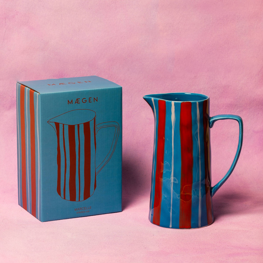 Blue and red striped pitcher with matching box on a pink background