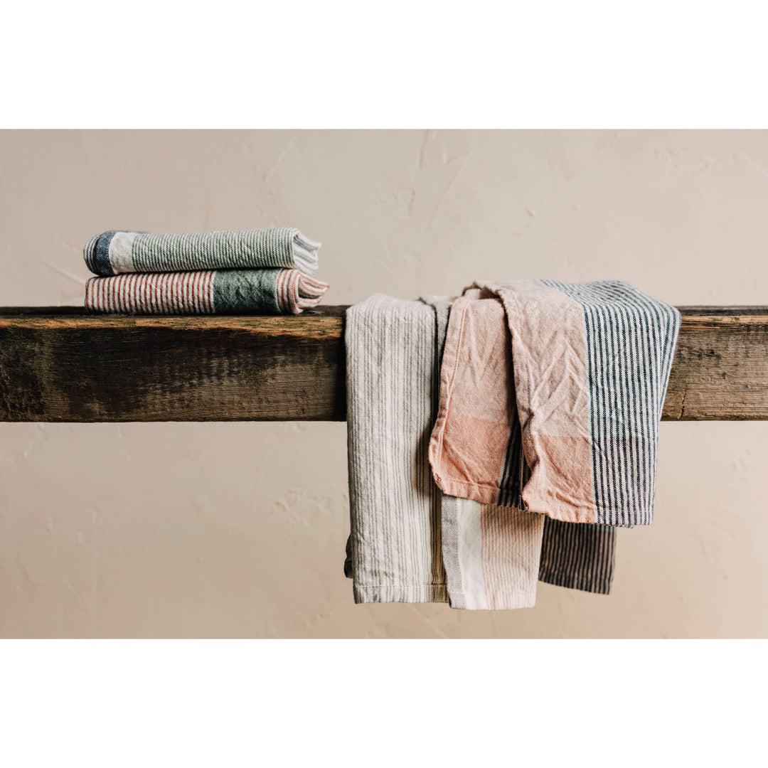 Stack of folded towels on a wooden surface against a beige wall