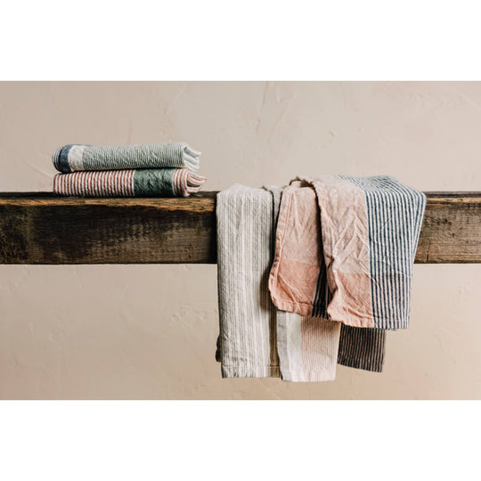 Stack of folded towels on a wooden surface against a beige wall
