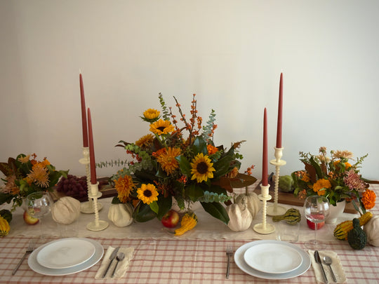 Thanksgiving themed floral centerpieces with candles and white plates