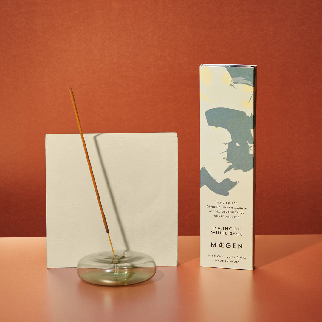 Incense stick in a glass holder with a branded box on a red background